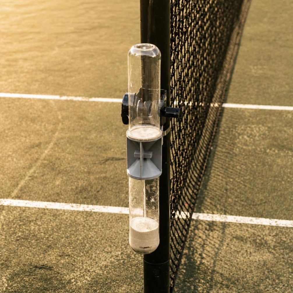 Close-up of the Ninety sand clock on a net post, sand running into the lower tube